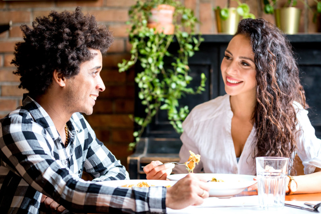 Young parents enjoying a meal of pasta